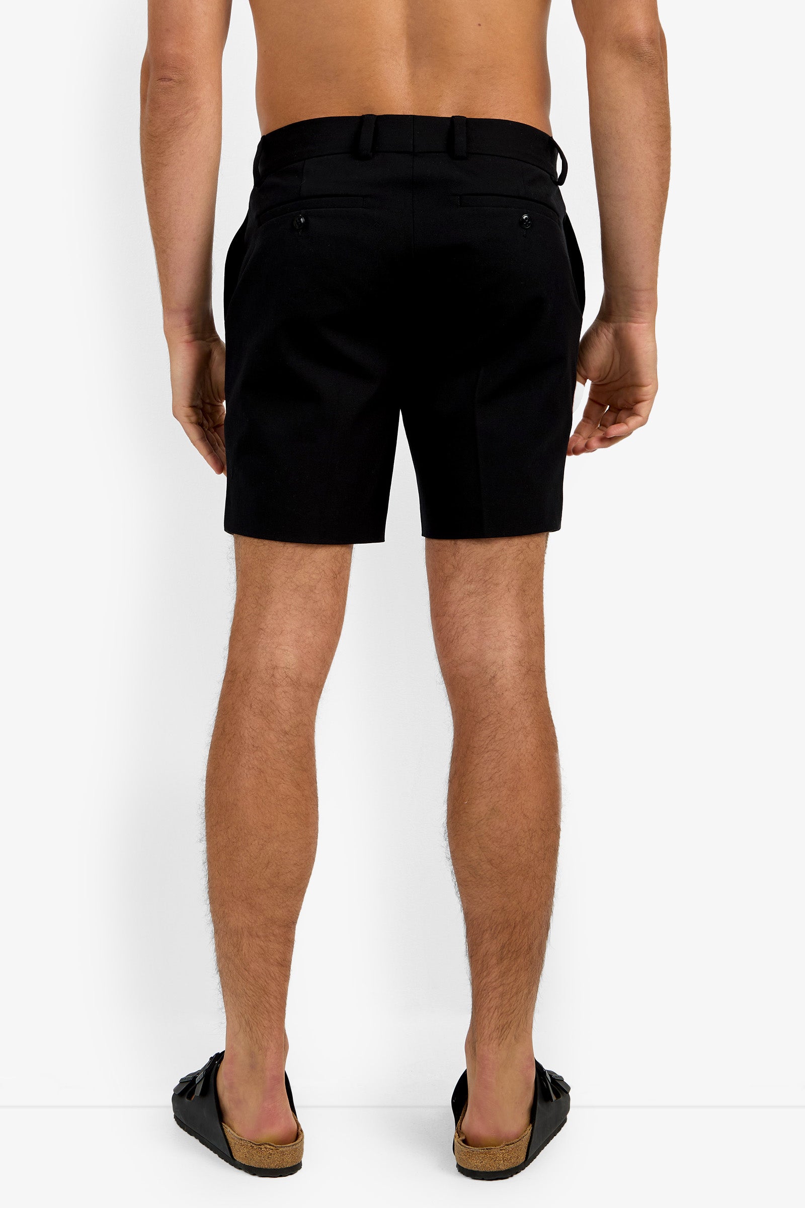 A shirtless person is shown from the back, wearing the Lawrence Short and black slip-on sandals, standing against a plain white background.
