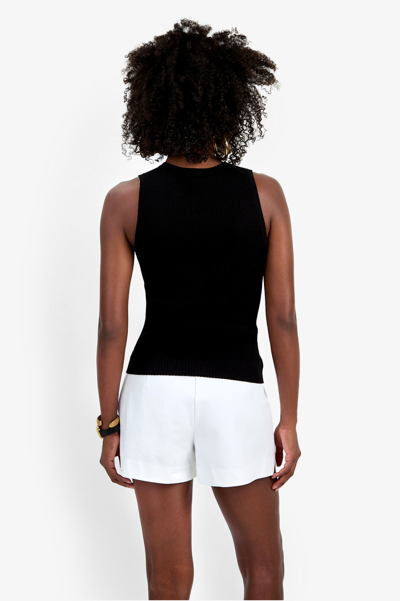 A person with curly hair stands with their back to the camera, wearing the Hampton Crewneck Top and white shorts against a plain white background.