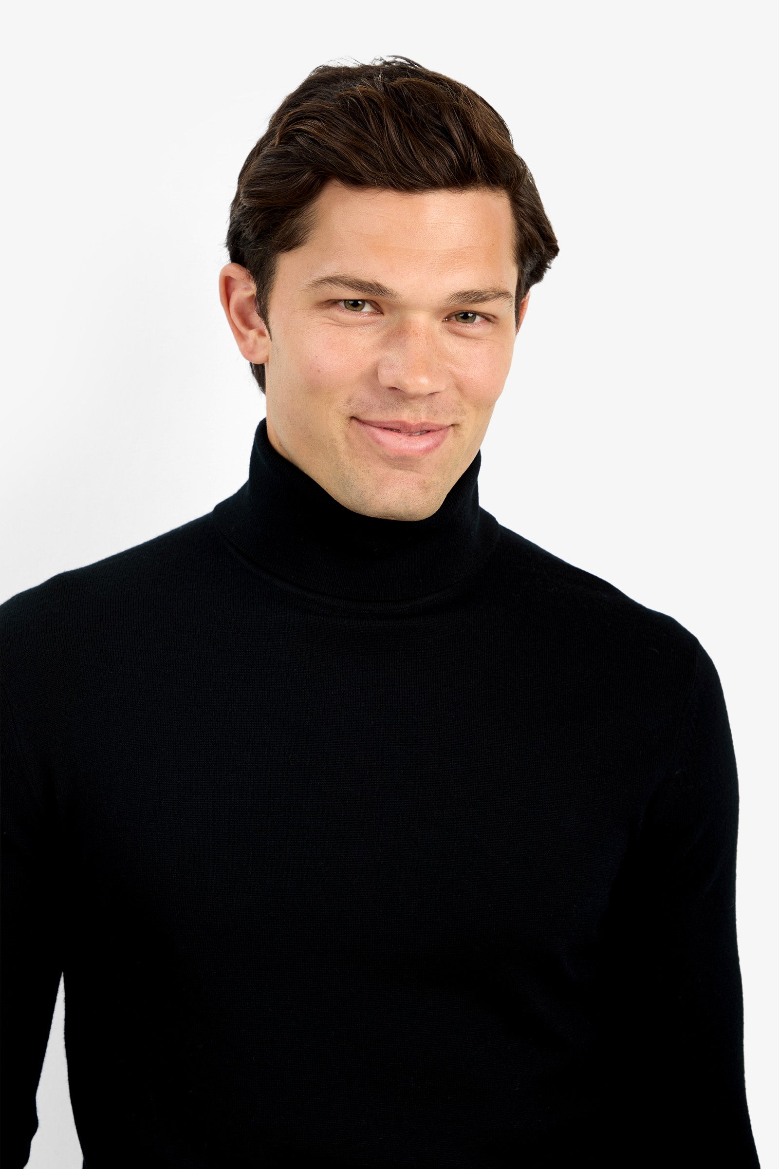 A man with short brown hair softly smiles while wearing the Roy Long Sleeve Turtleneck, standing against a plain white background.
