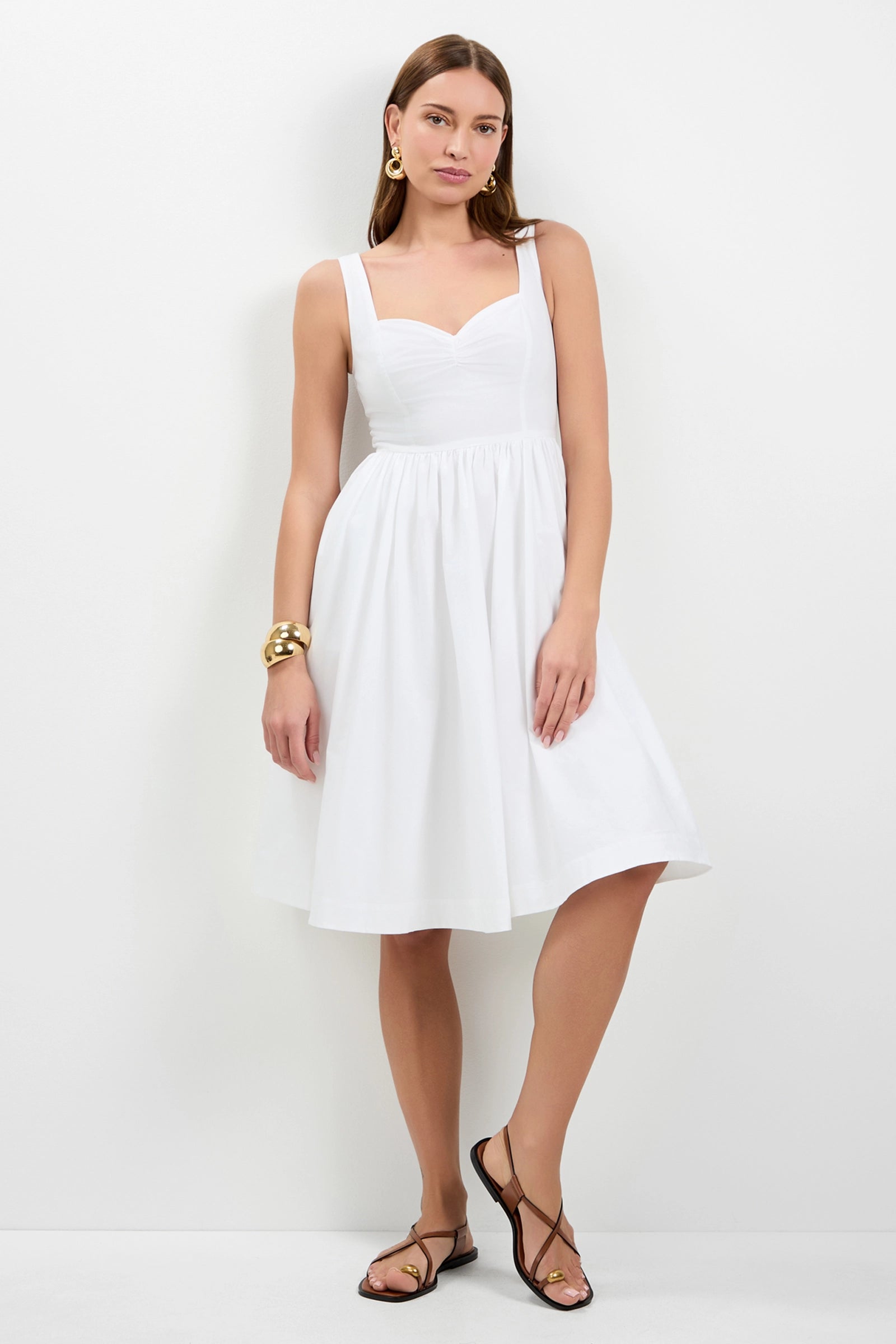 A woman stands against a white background wearing the Mirabello Sweetheart Neck Midi Dress, styled with gold earrings, gold bracelets, and black strappy sandals.
