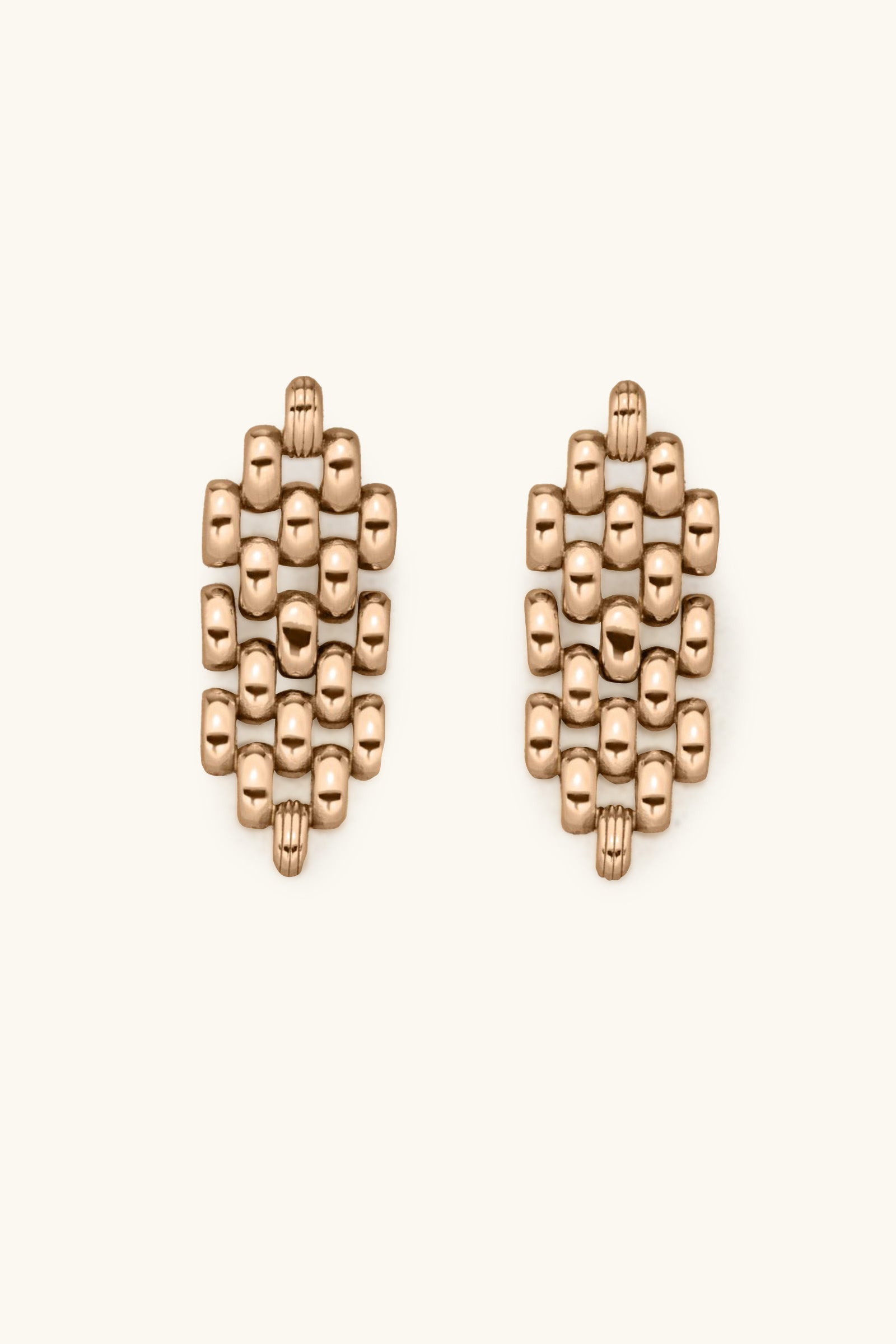 The Phoebe Earrings are gold, featuring a geometric cluster of small, rounded square beads arranged in an oval pattern on a light background.