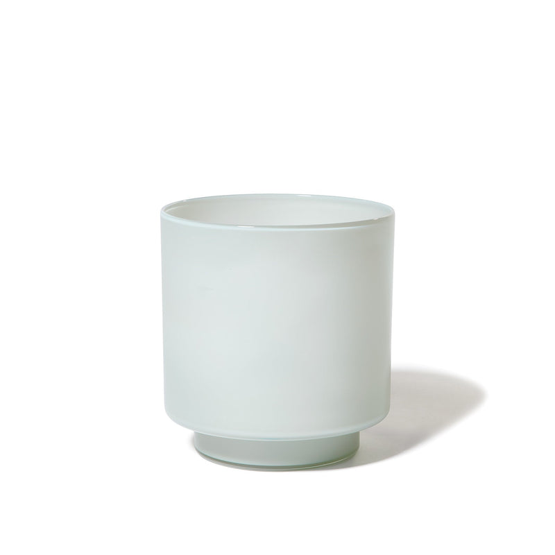 The Fiorelli Low Container, a simple cylindrical vessel in ash, sits on a white background, casting a soft shadow to the right.