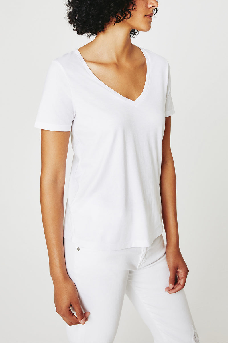 A person models the AG Jager Vee Tee - White with white pants against a white background, head turned slightly to the side, showing only their upper body.