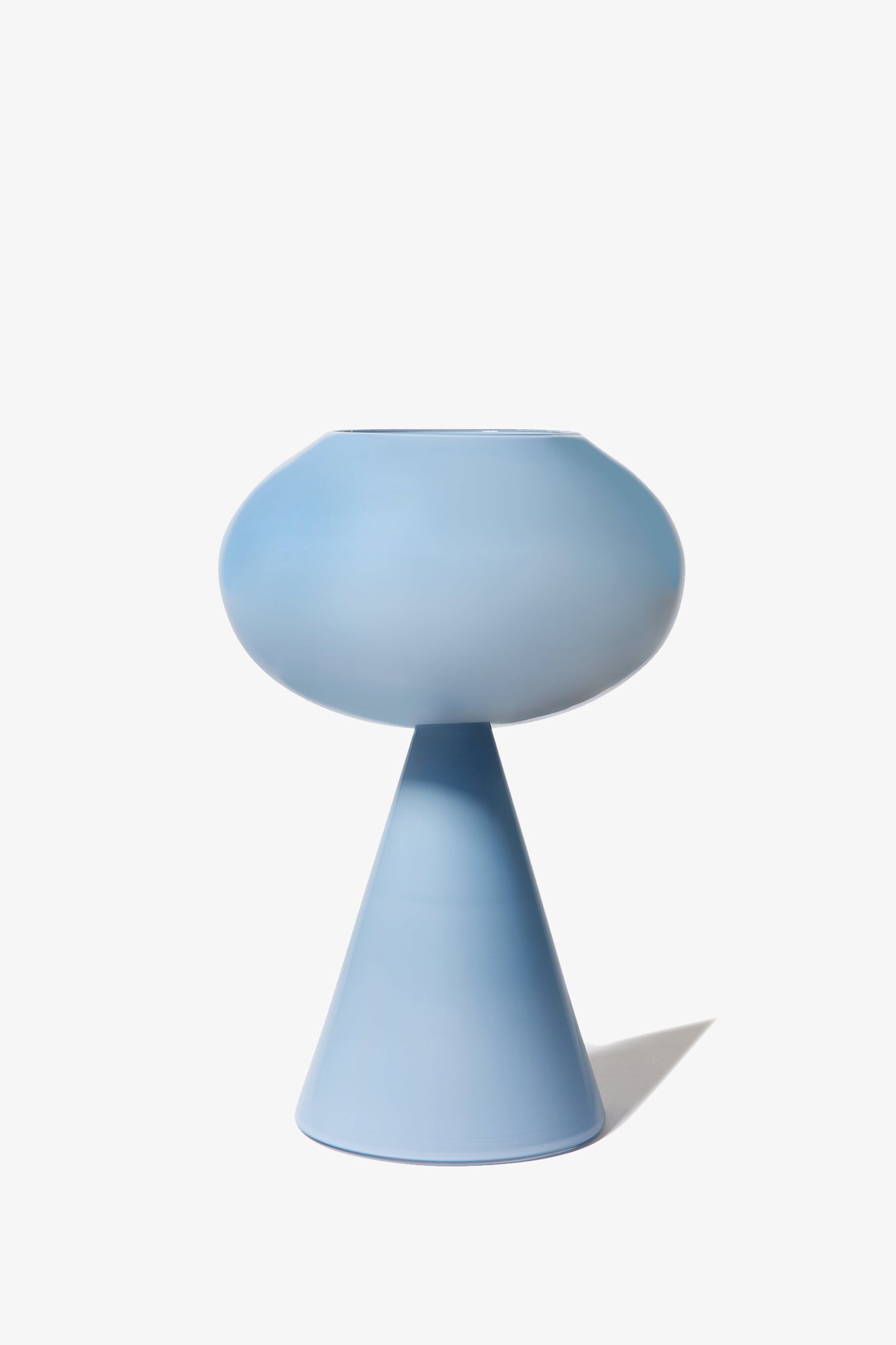 The Fiorelli Concave is a modern, matte light blue vase featuring a round top and a cone-shaped base, displayed against a plain white background.