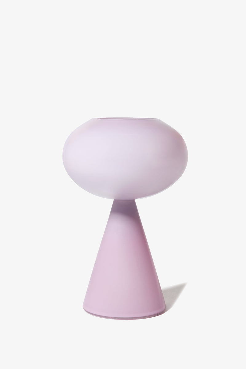 The Fiorelli Concave is a modern, minimalist vase in light pastel pink, featuring a round top and a cone-shaped base, displayed against a plain white background.