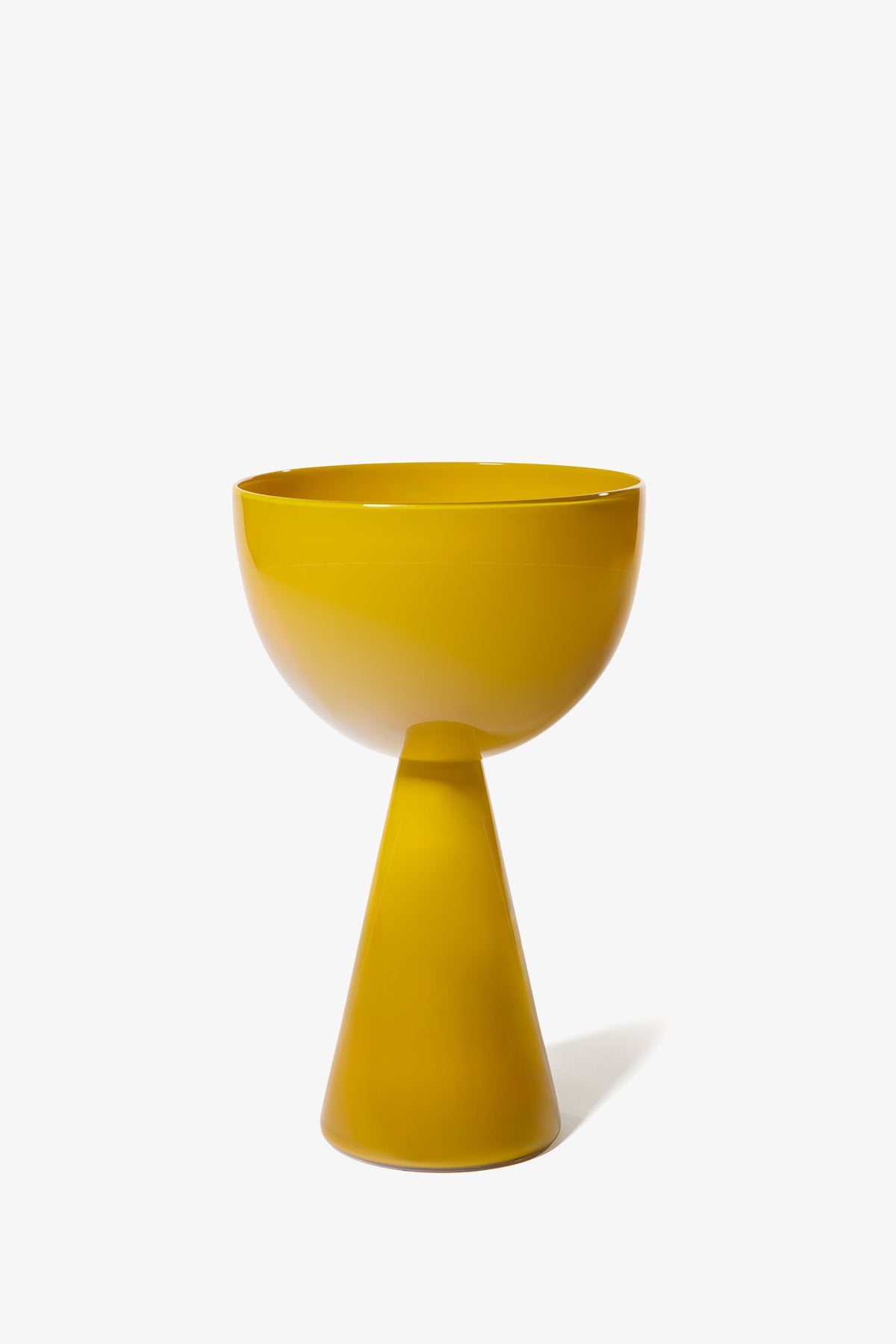 The Fiorelli Low Bowl is a modern, glossy yellow pedestal bowl featuring a round top and a conical base, set against a plain white background.