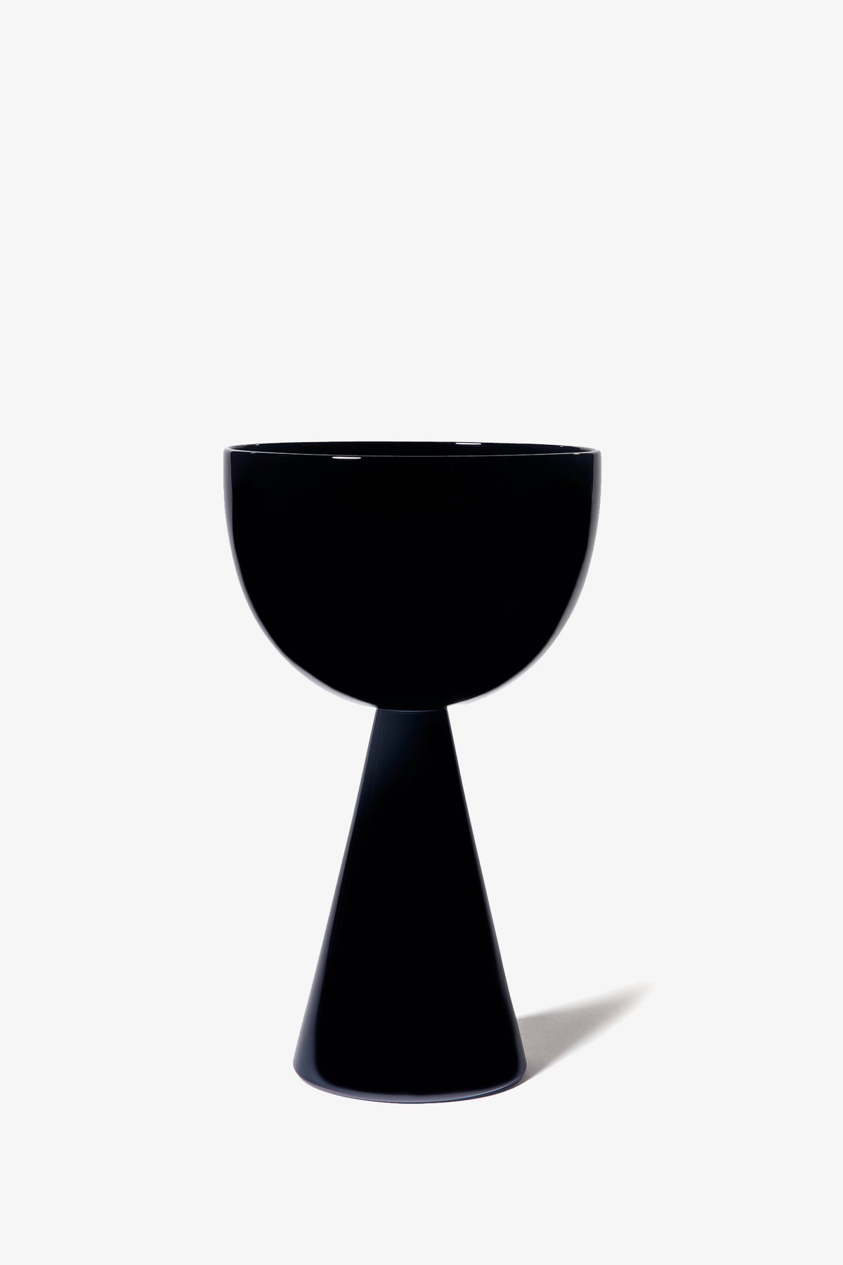 The Fiorelli Low Bowl is a black, modern, sculptural vessel featuring a wide, round bowl atop a conical base, set against a plain white background.