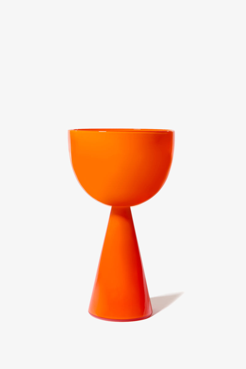 A modern, bright orange Fiorelli Low Bowl with an hourglass shape and a glossy ceramic finish, displayed on a white background and casting a soft shadow to the right.