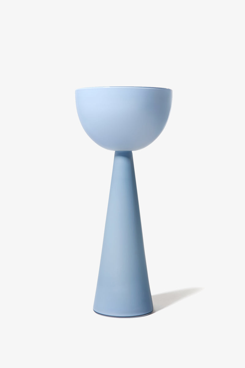 The Fiorelli Tall Bowl features a modern, minimalist design with a cone-shaped base and a wide, shallow bowl on top, finished in matte light blue and set against a plain white background.