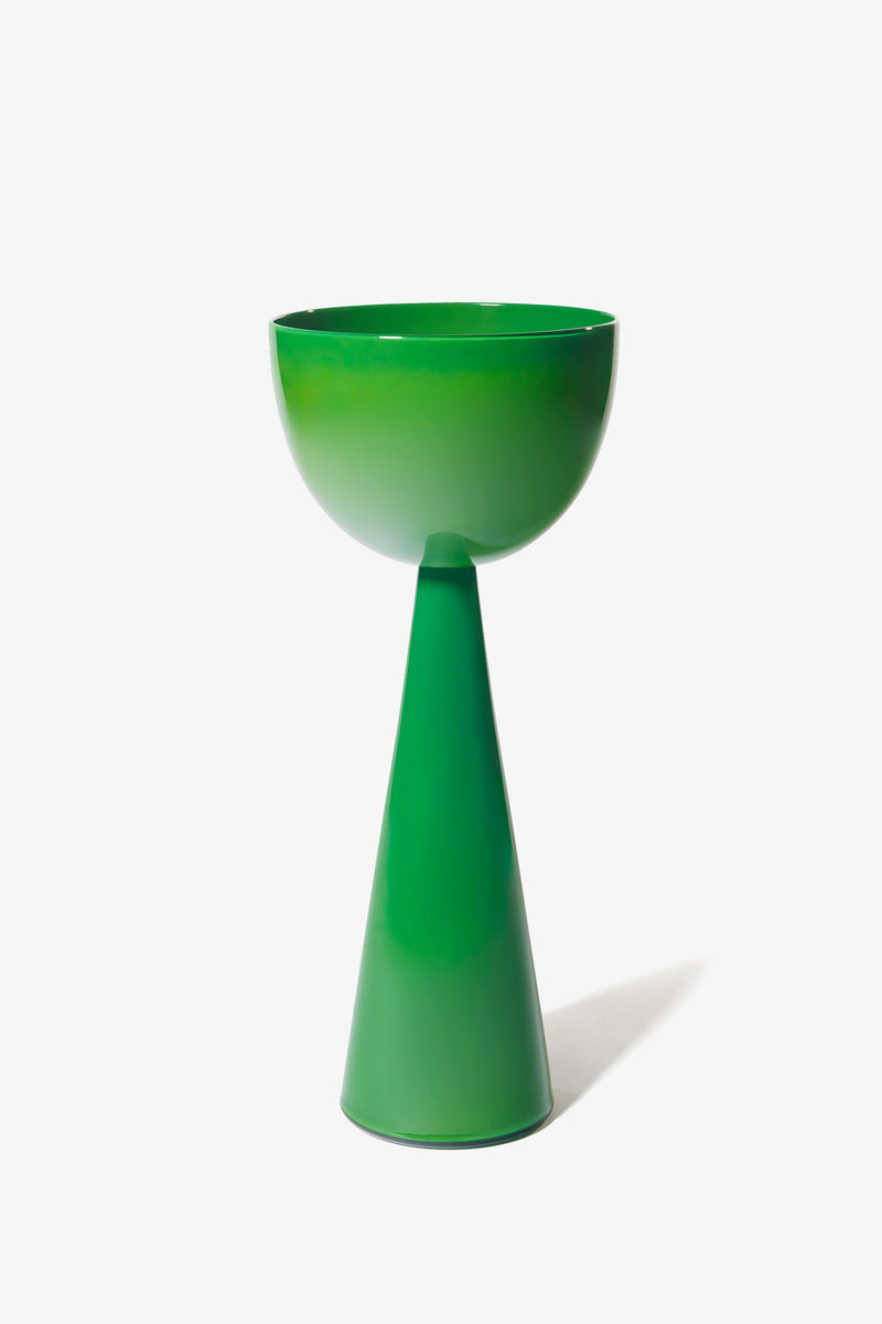 The Fiorelli Tall Bowl is a green, modern pedestal bowl with a glossy finish. It features smooth lines and a minimalist design, with the bowl resting atop a tall, conical base. The piece is presented against a plain white background.