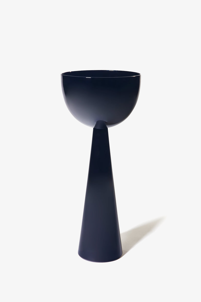 The Fiorelli Tall Bowl is a modern, minimalist pedestal planter featuring a dark blue finish, with a conical base and a wide, rounded bowl on top, photographed against a plain white background.