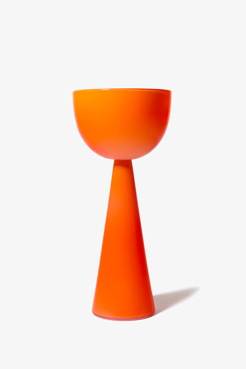 The Fiorelli Tall Bowl features a modern design in bright orange, with a wide, round top and a conical pedestal base, showcased against a plain white background.