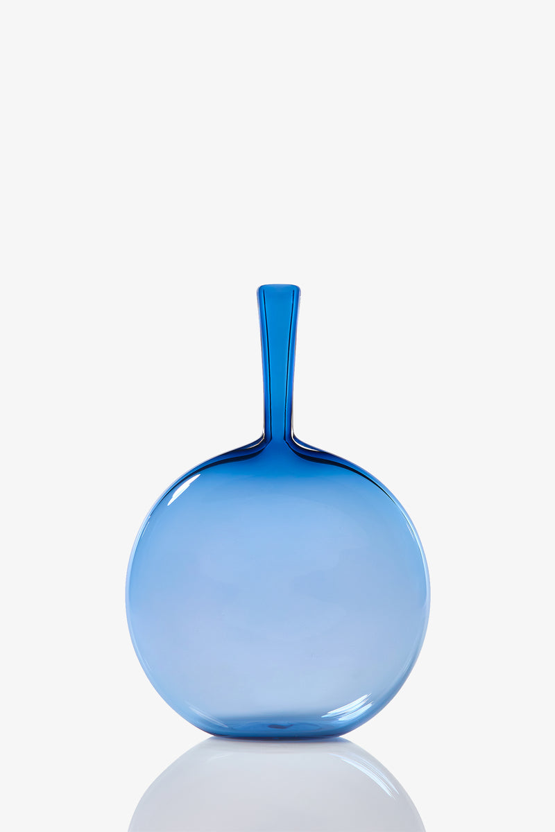 The Flask Angelic Bottle is a round, flat vase with a narrow neck, crafted from translucent blue glass and shown against a plain white background.