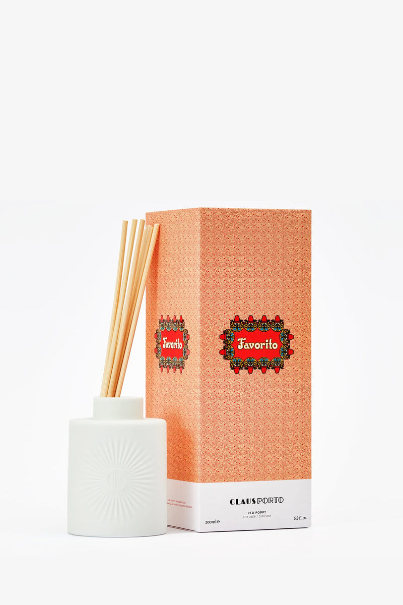 The Claus Porto Favorito Diffuser with reed sticks is displayed next to its patterned orange box on a white background.