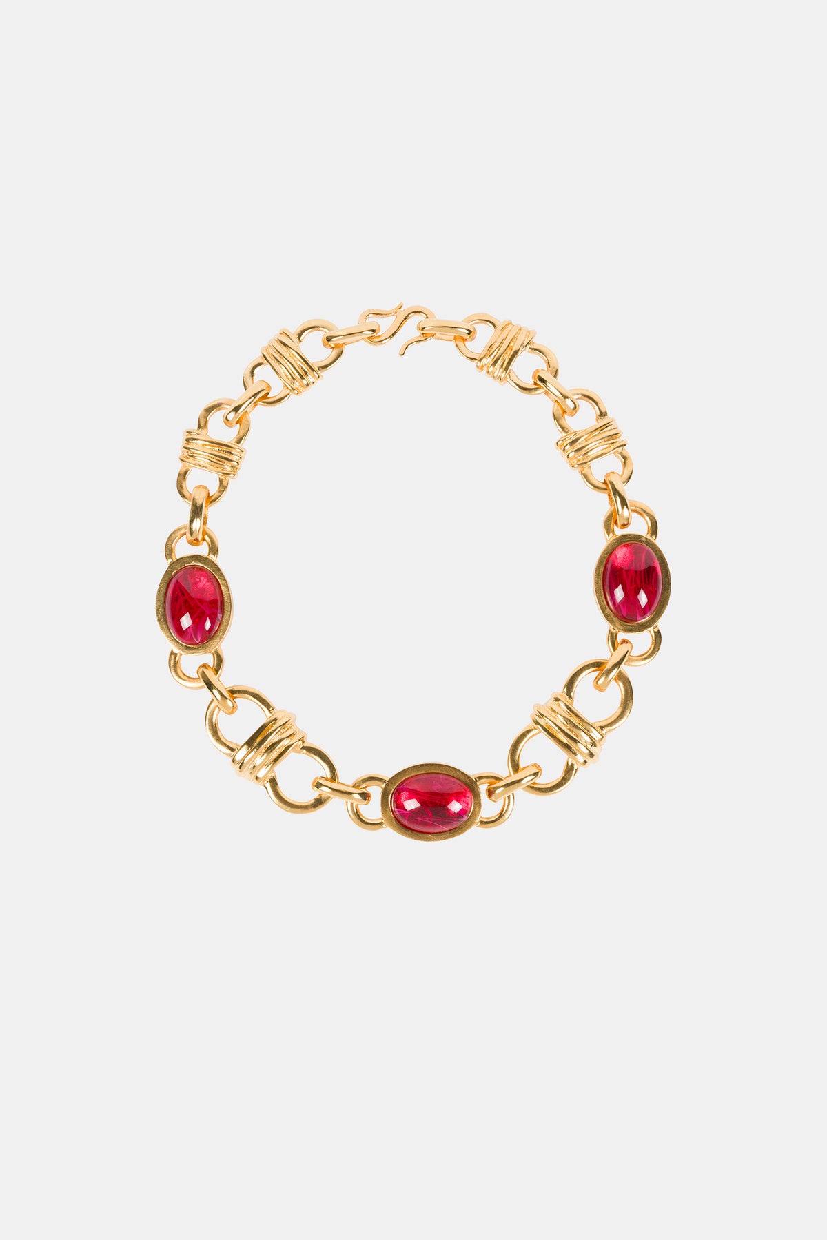 The Ruby Oval Link Necklace features three evenly spaced oval red gemstones set in gold links with intricate wire detailing, showcased on a plain white background.