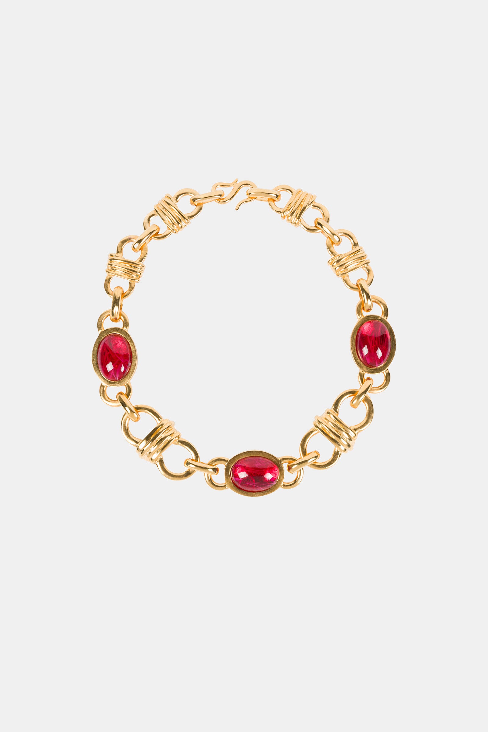The Ruby Oval Link Necklace features three evenly spaced oval red gemstones set in gold links with intricate wire detailing, showcased on a plain white background.