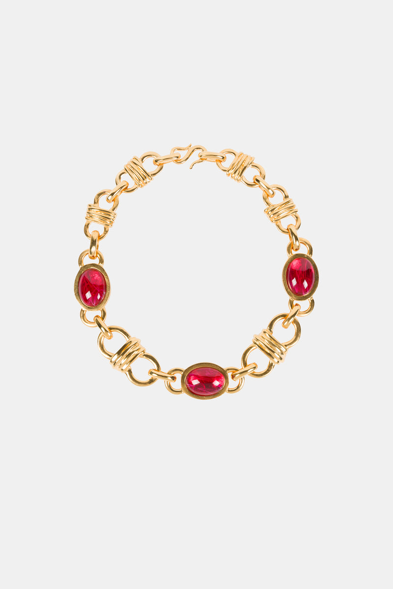 The Ruby Oval Link Necklace features three evenly spaced oval red gemstones set in gold links with intricate wire detailing, showcased on a plain white background.