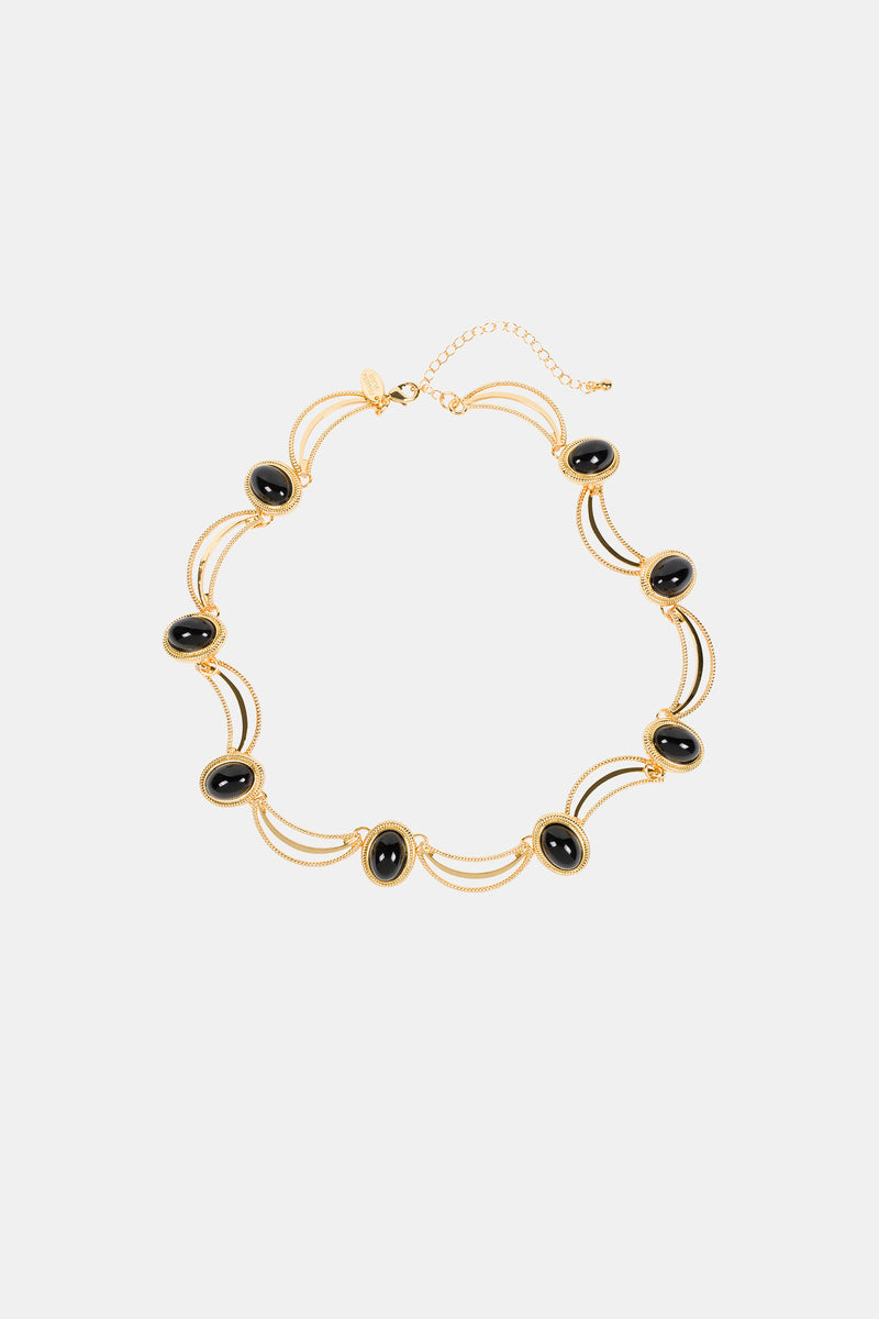 The Oval Jet Scallop Necklace features black oval stones in gold frames, joined by double gold chains and an adjustable clasp. Its elegant, symmetrical design makes it a standout accessory.