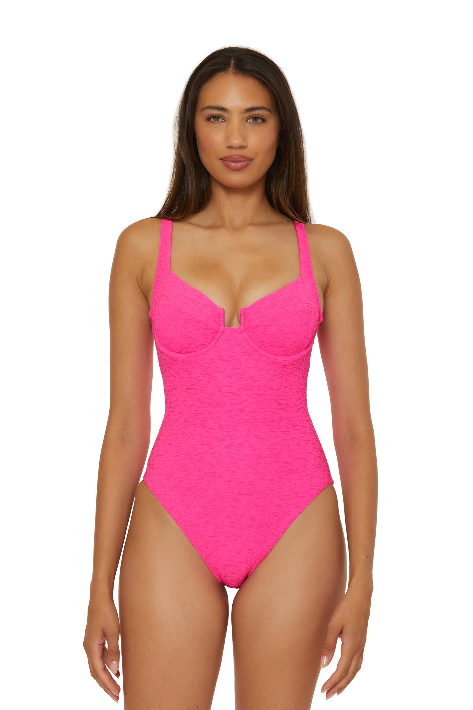 A woman with long straight hair faces forward, wearing the Underwire One-Piece Swimsuit - Indio in Love All Pink, featuring adjustable straps and a structured bust. She poses with a neutral expression against a plain white background.