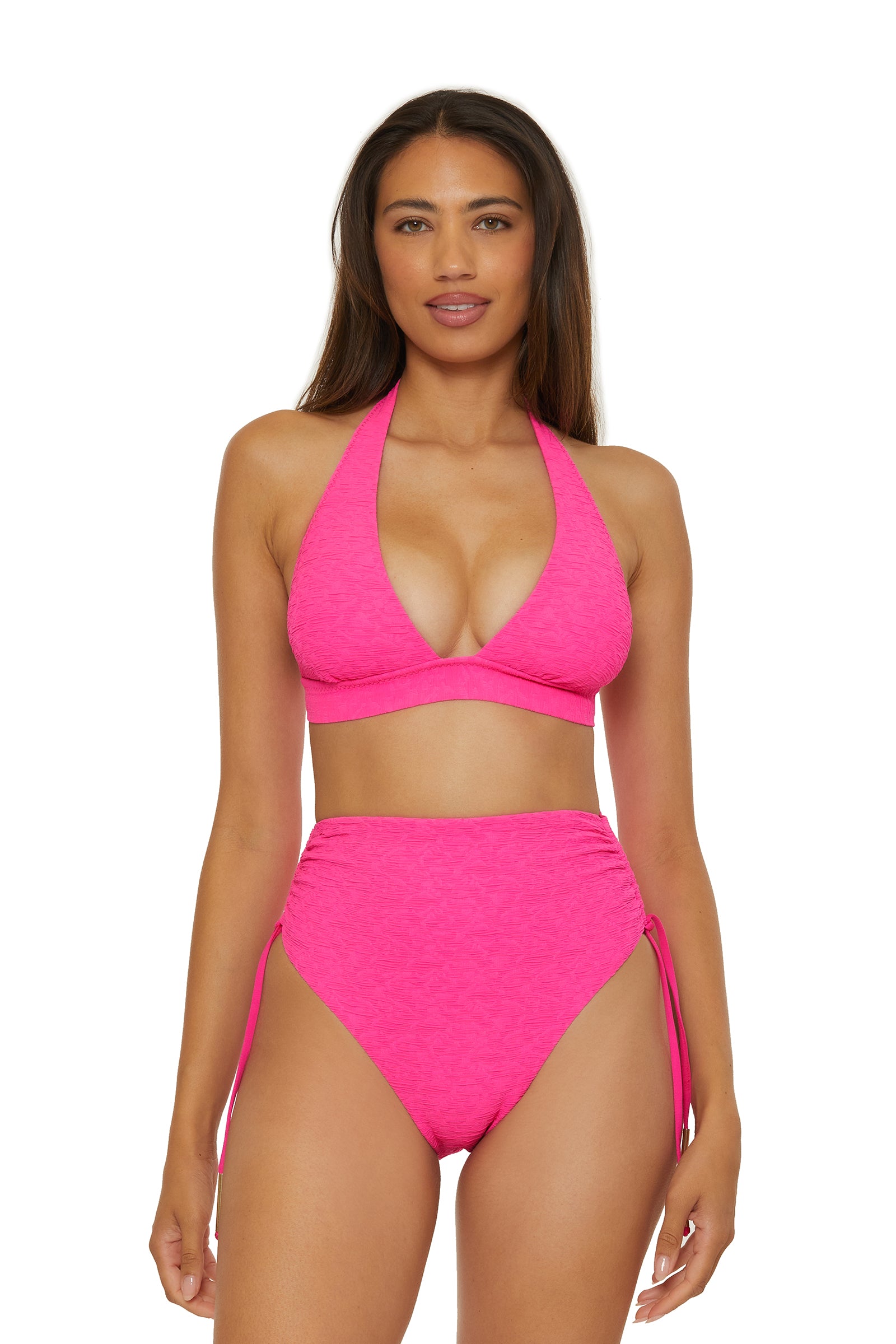 A woman faces forward, wearing Shirred High-Waist Swim Bottom - Indio in bright pink with a matching halter bikini top. Her long straight brown hair frames her neutral expression against a plain white background.