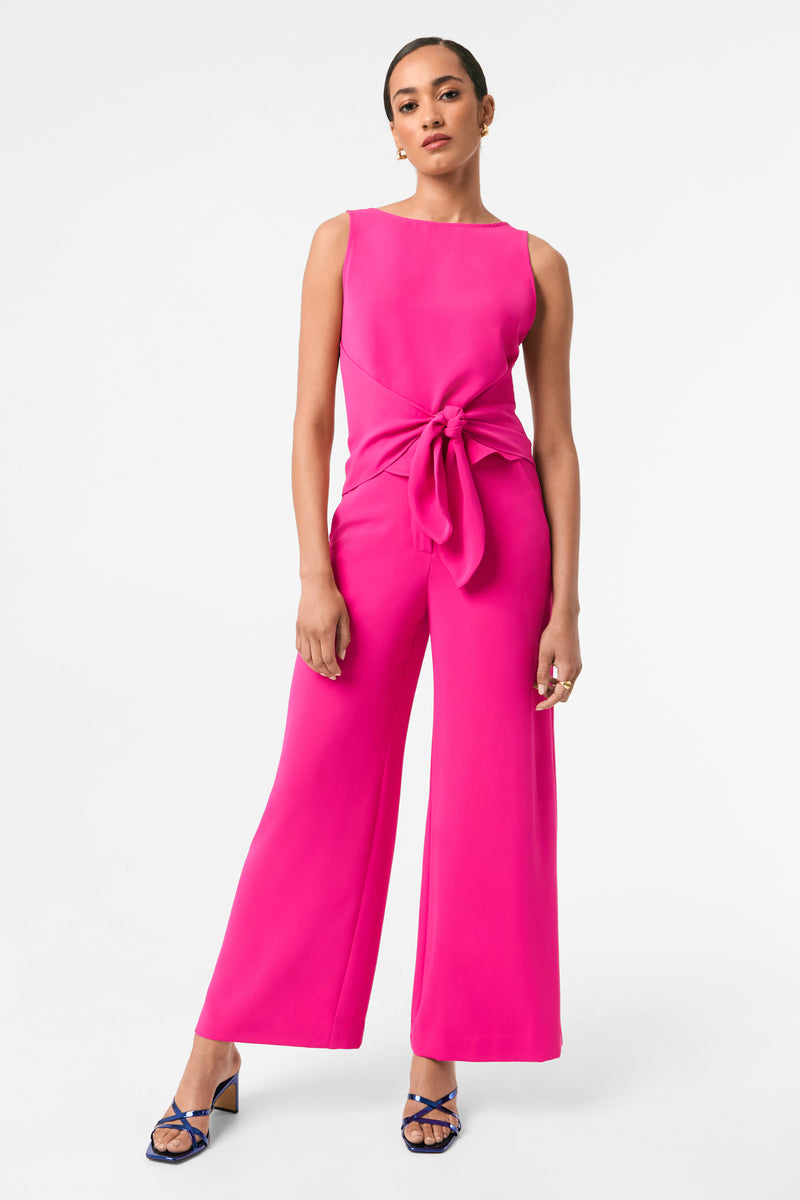Woman wearing a bright pink jumpsuit on a white background
