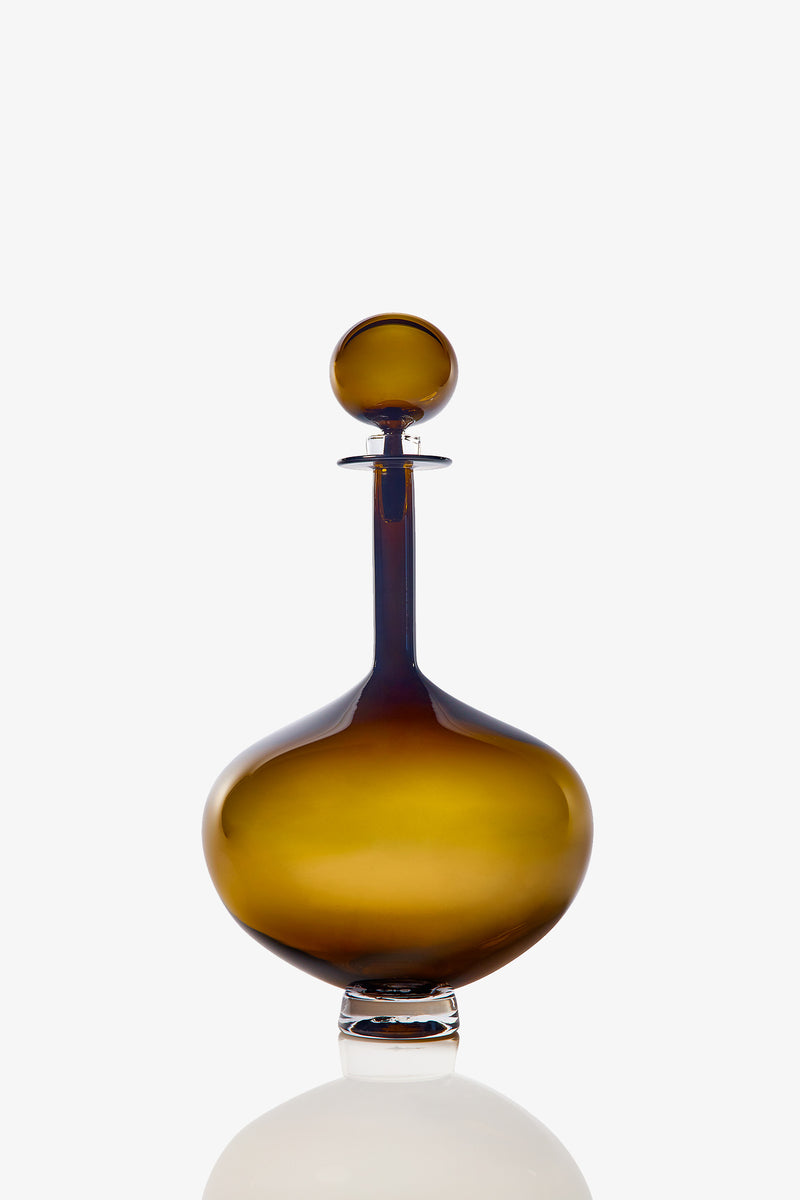 A Large Genie Bottle Decanter with a round stopper sits on a reflective surface against a plain white background.