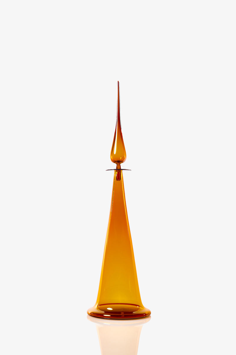 A large fluted cone decanter, featuring tall amber-colored glass with a conical base and a slender, pointed top, set against a plain white background.