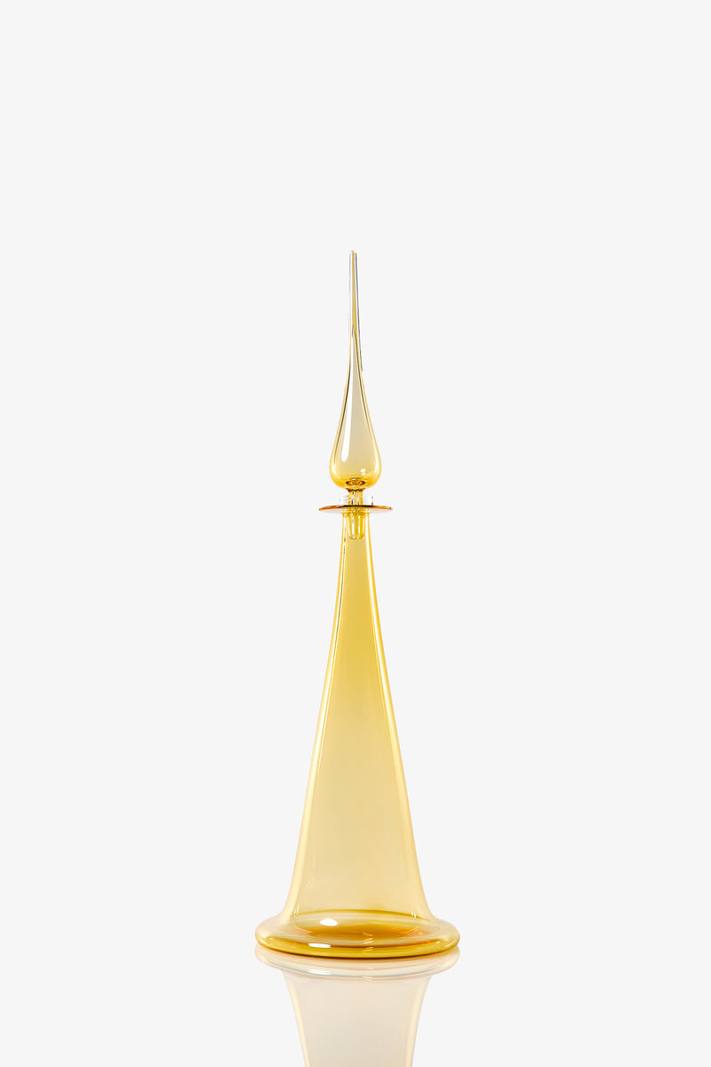 A Large Fluted Cone Decanter, featuring an elegant, tall amber-colored glass body with a pointed stopper and wide base, is displayed against a plain white background.
