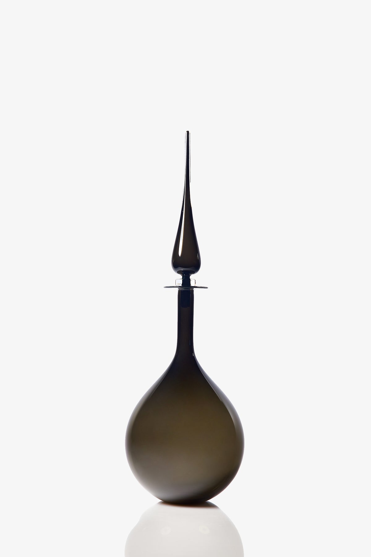 A Large Tear Drop Decanter with a dark, opaque glass body, wide base, and long pointed stopper stands upright against a white background, casting a faint reflection below.