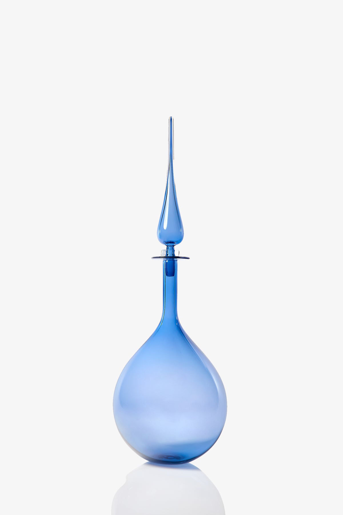 A large, elegant blue glass tear drop decanter with a rounded base and a long, pointed stopper, displayed against a plain white background.