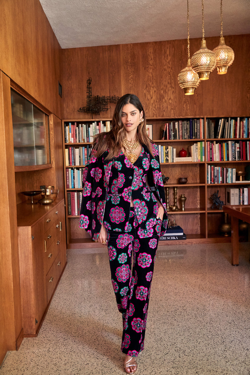 A person wearing a black blazer and matching Westport Pant with a repeating pink and green floral pattern.