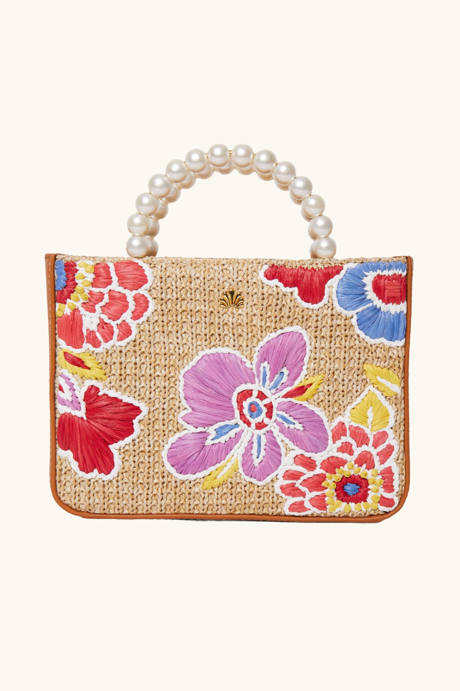 The Lele Sadoughi x Trina Turk Maya Floral Mini Tote in Natural is a woven straw handbag with red, purple, blue, and yellow embroidered flowers and a handle made of large pearl-like beads.