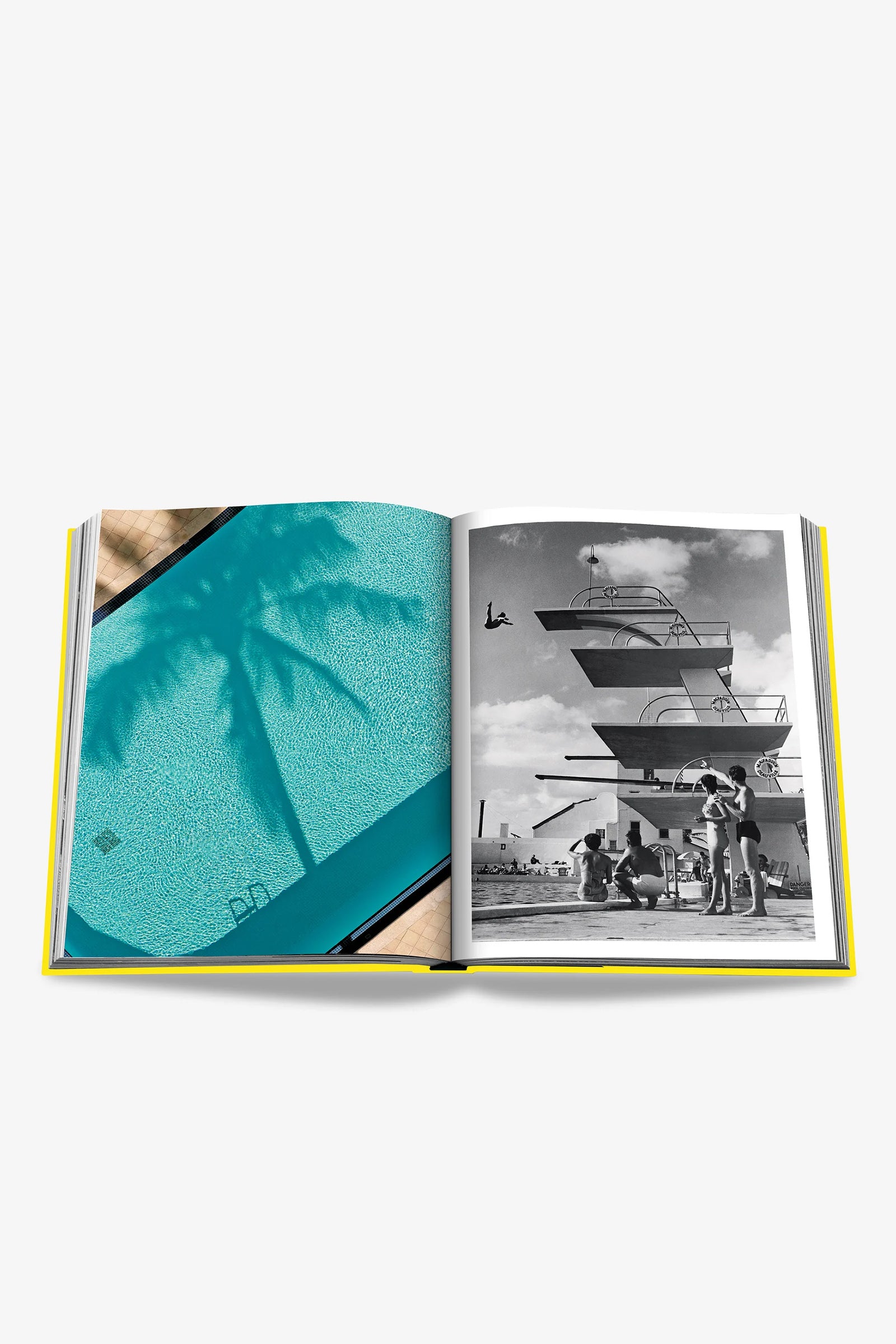 The Assouline Miami Beach Book is open to a spread featuring a color photograph of a swimming pool with the shadow of a palm tree on the left page and a black-and-white image of people gathered by a diving platform on the right page.