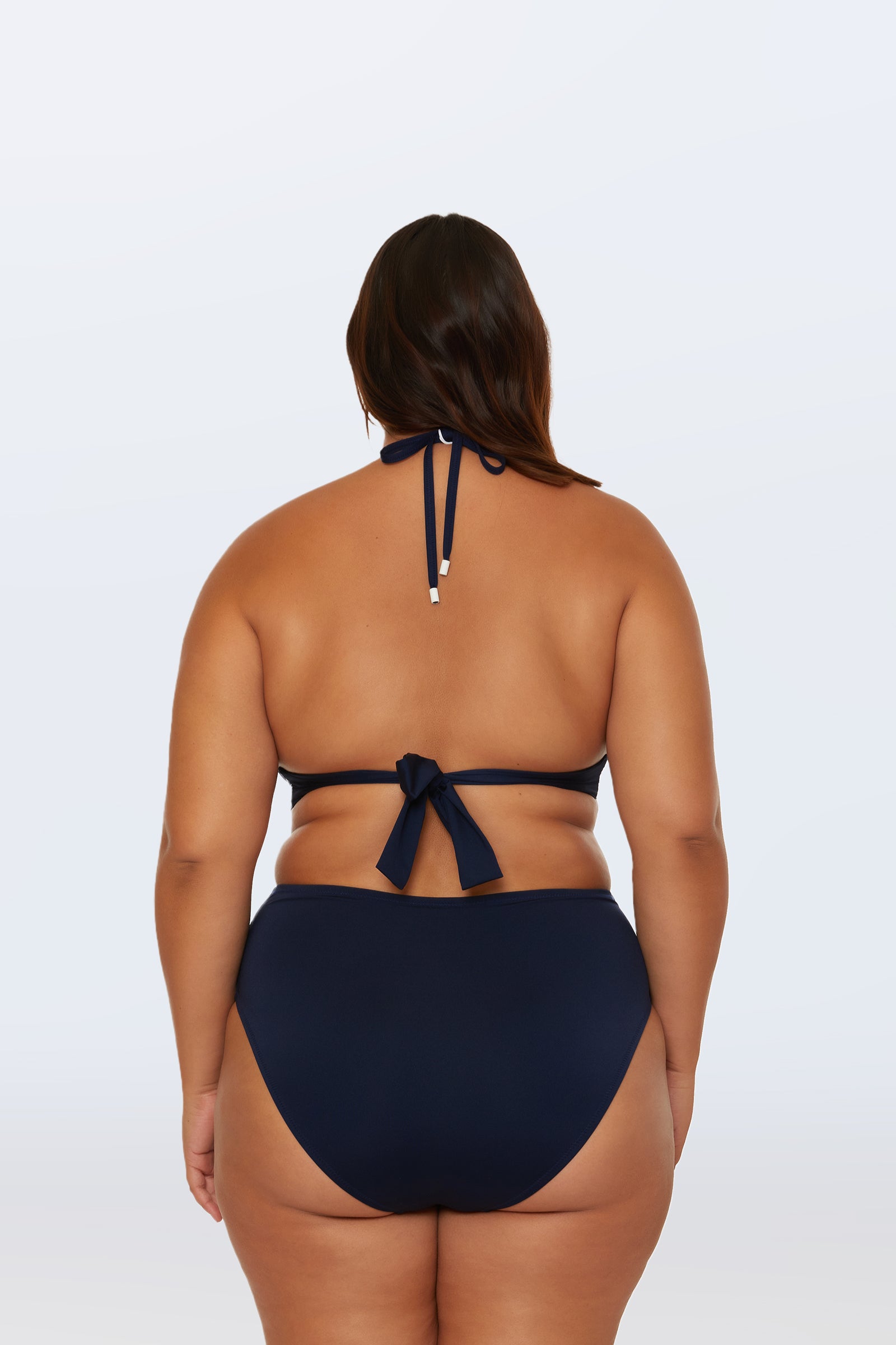 A woman with long brown hair is shown from the back against a white background, wearing a dark blue halter bikini with the Monaco Pleated High-Waist Bikini Bottom.