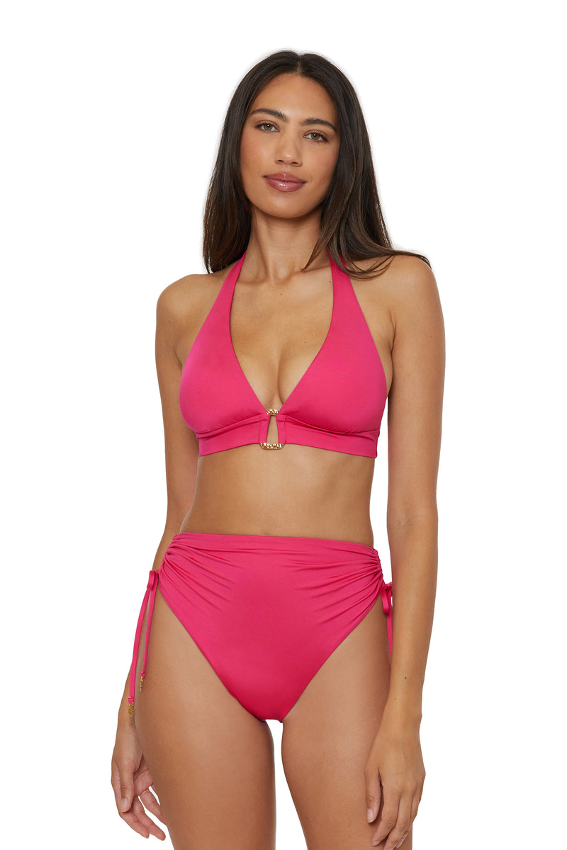 A woman with long dark hair wears a bright pink halter bikini top and Monaco Shirred Tie High-Waist Swim Bottoms, standing against a white background and looking at the camera.