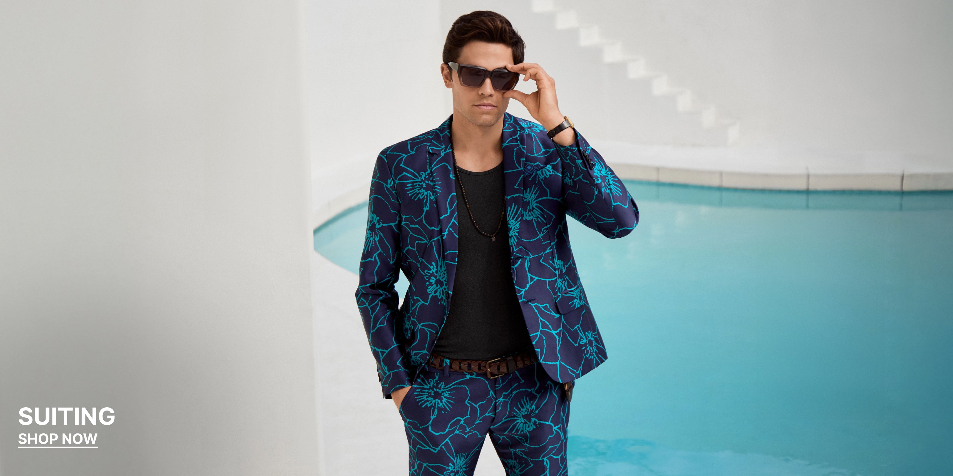 Man wearing a blue patterned suit standing by a pool.