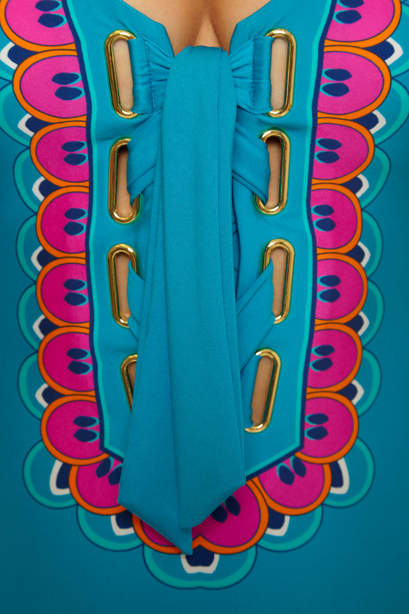 Close-up of the Mykonos Lace Up Maillot: a vibrant turquoise swimsuit with gold eyelets, wide blue lacing, and a colorful scalloped pattern in pink, orange, and purple around the lace-up front.