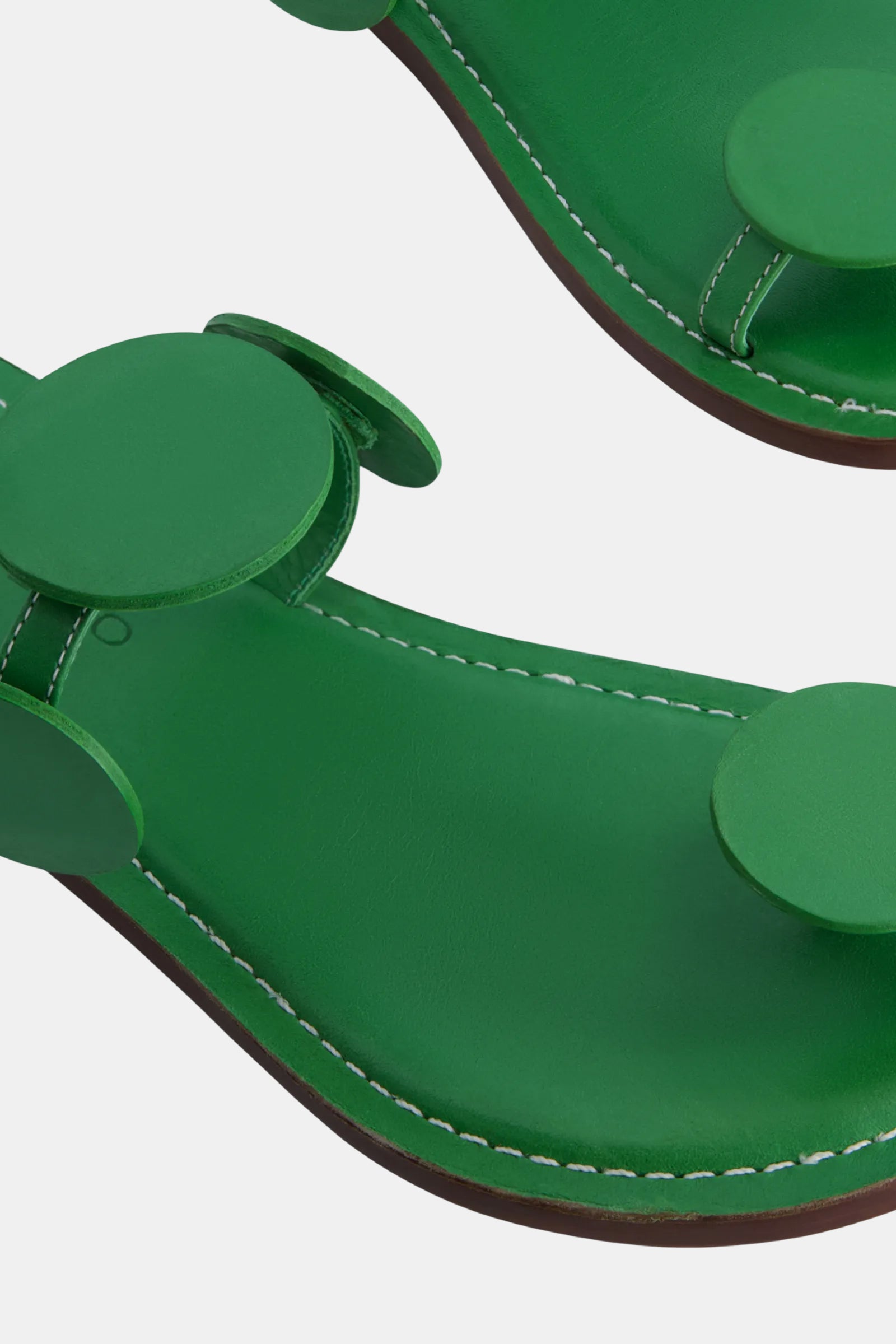 Close-up of the Bernardo New Moon Sandal in green, featuring circular green decorative accents and white stitching along the edge, shown on a plain background.