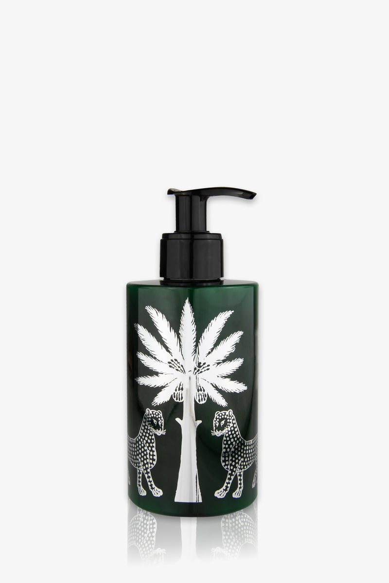 An amber pump bottle of Ortigia Ambra Nera Lotion, featuring a white illustration of a palm tree with two leopards facing each other, one on each side. The background is plain white.