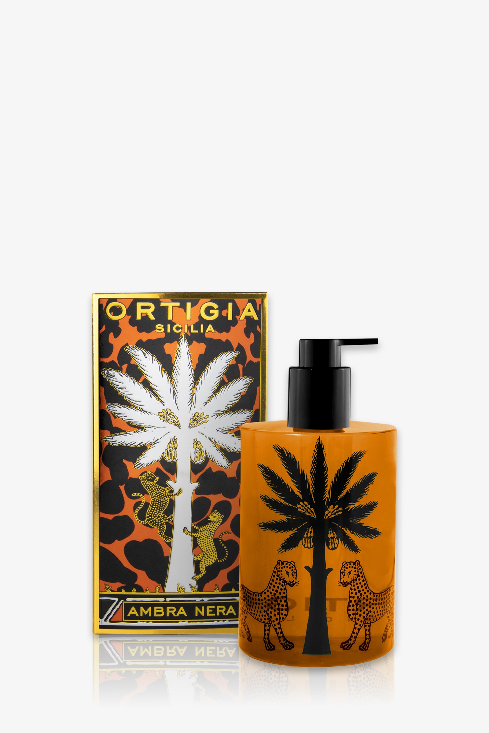 An orange bottle of Ortigia Ambra Nera Shower Gel with a black pump, featuring black palm tree and leopard designs, is displayed in front of its matching decorative box.