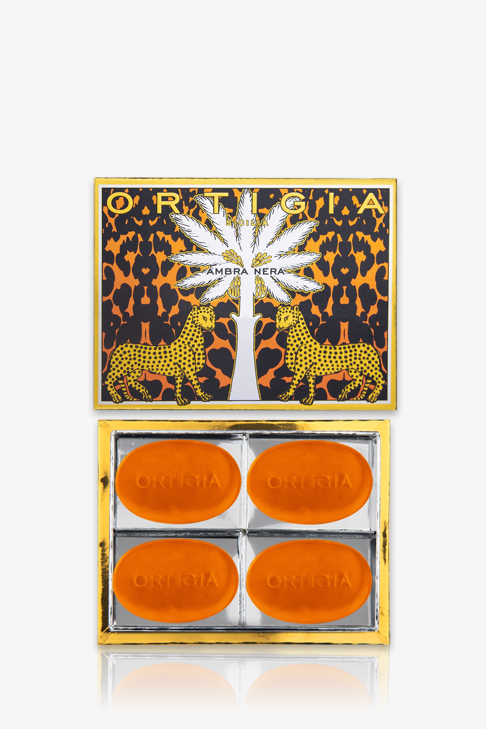 The Ortigia Ambra Nera Soap 4P Set features four oval amber soaps in a decorative box with a palm tree and cheetah design, arranged in a clear tray.
