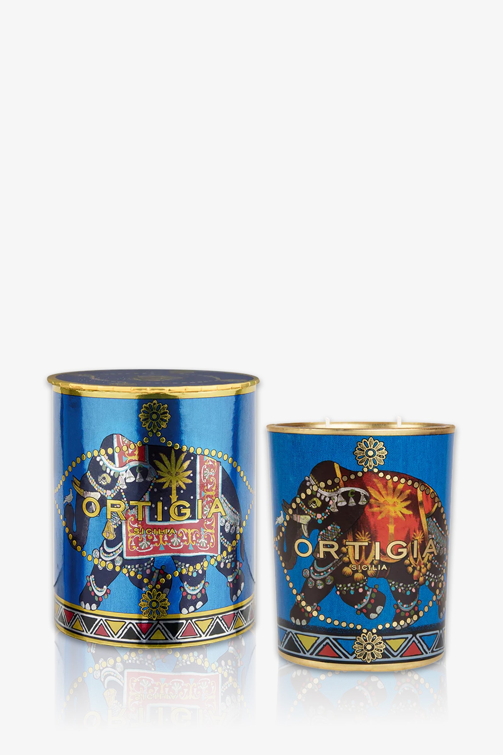 The Ortigia Sandalo Medium Candle in blue features ornate elephant and pattern designs, with one candle lidded and one open; both exude a luxurious, exotic style.
