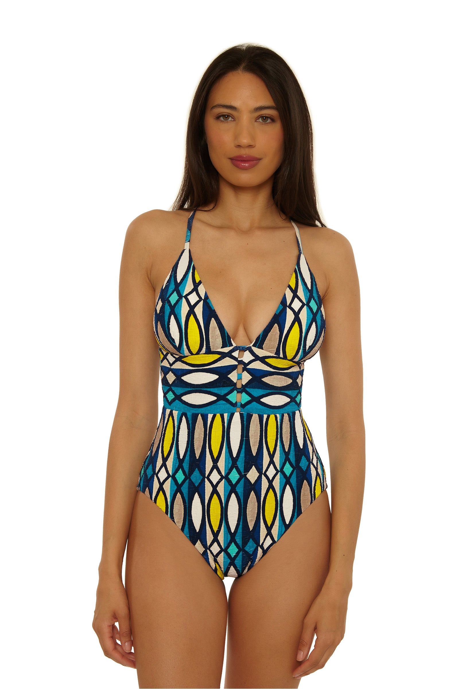 A woman with long brown hair faces forward in the Paros Empire Waist Maillot, a one-piece swimsuit with a geometric pattern in blue, yellow, white, and black. She stands against a plain white background.