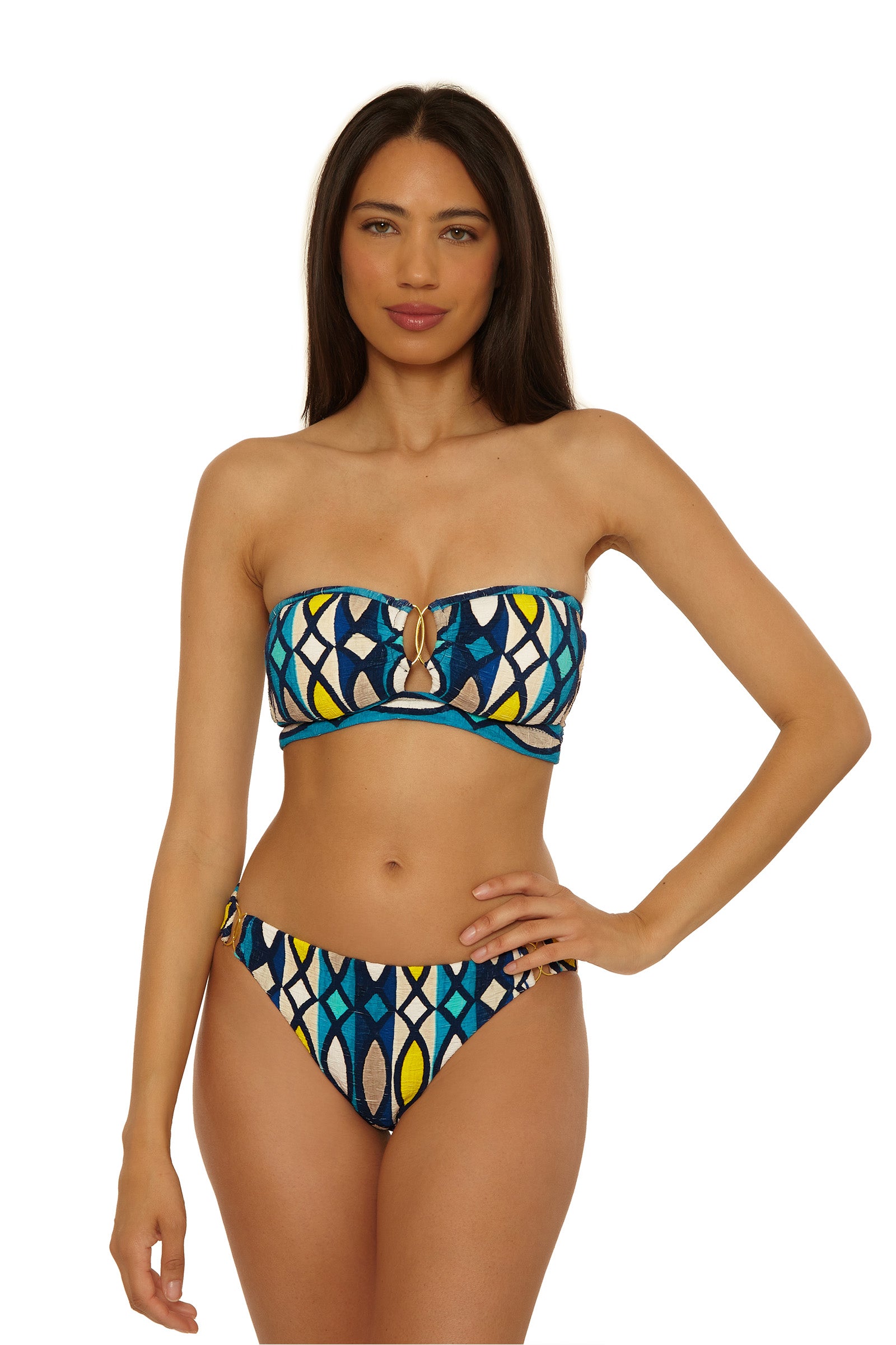 A woman with long dark hair models the Paros Banded Bandeau Top, a colorful strapless bikini featuring blue, yellow, black, and white patterns, against a plain white background.