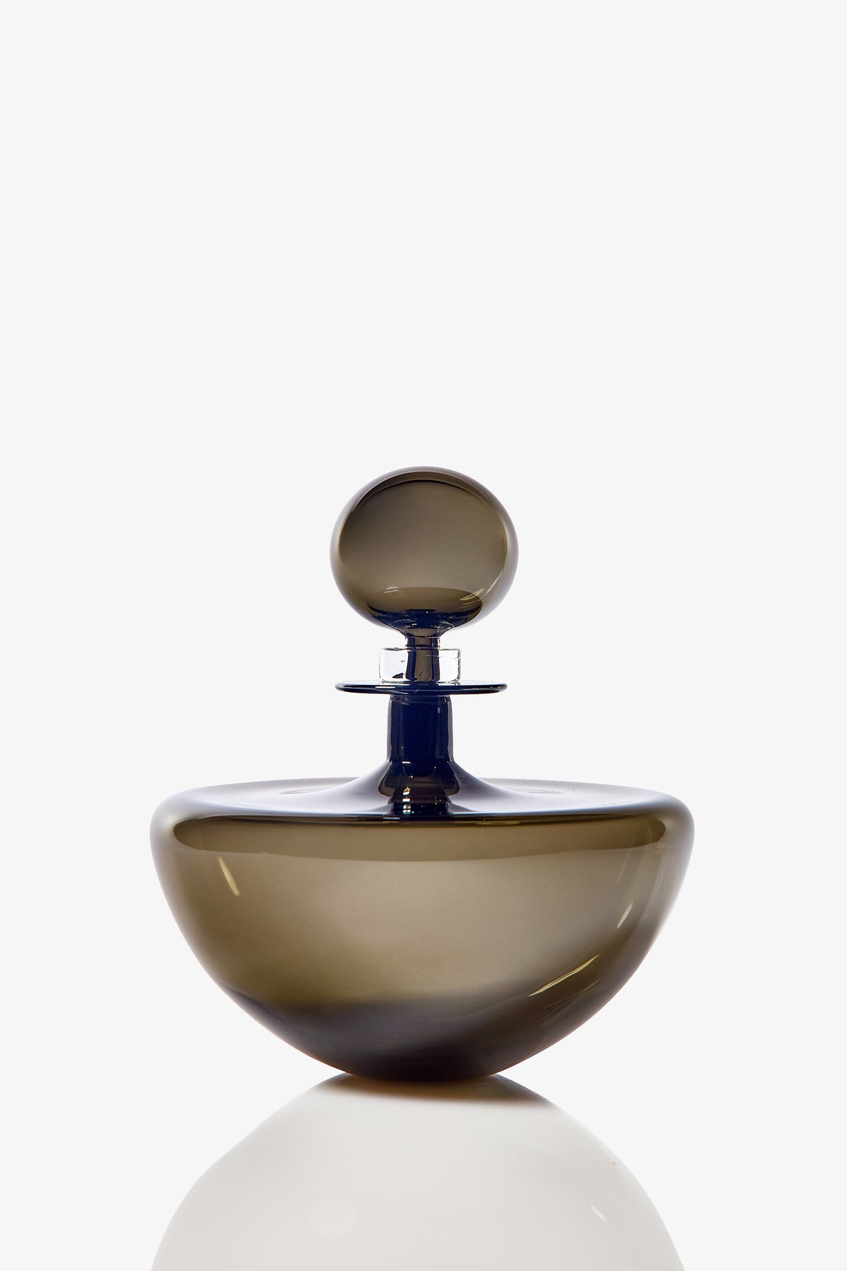 The Small Angelic Bottle is a sleek, round perfume bottle made of translucent brown glass with a matching spherical stopper, shown against a white background with a faint reflection underneath.
