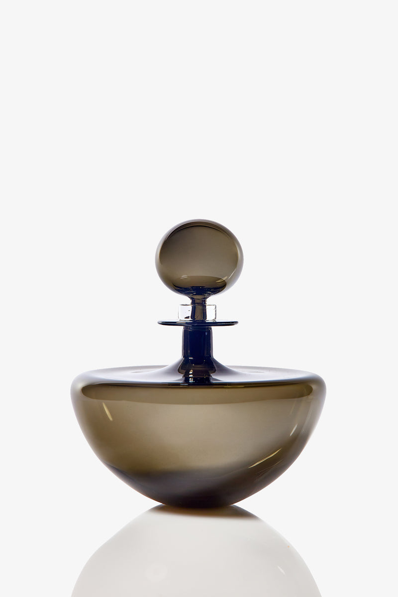 The Small Angelic Bottle is a sleek, round perfume bottle made of translucent brown glass with a matching spherical stopper, shown against a white background with a faint reflection underneath.