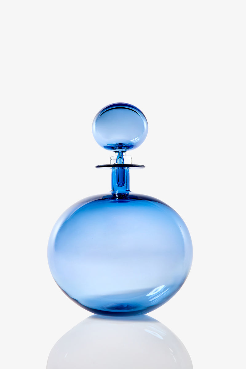 The Small Angelic Bottle is a round, translucent blue glass perfume bottle with a spherical stopper. Shown on a plain white background, its glossy surface reflects light for an elegant effect.