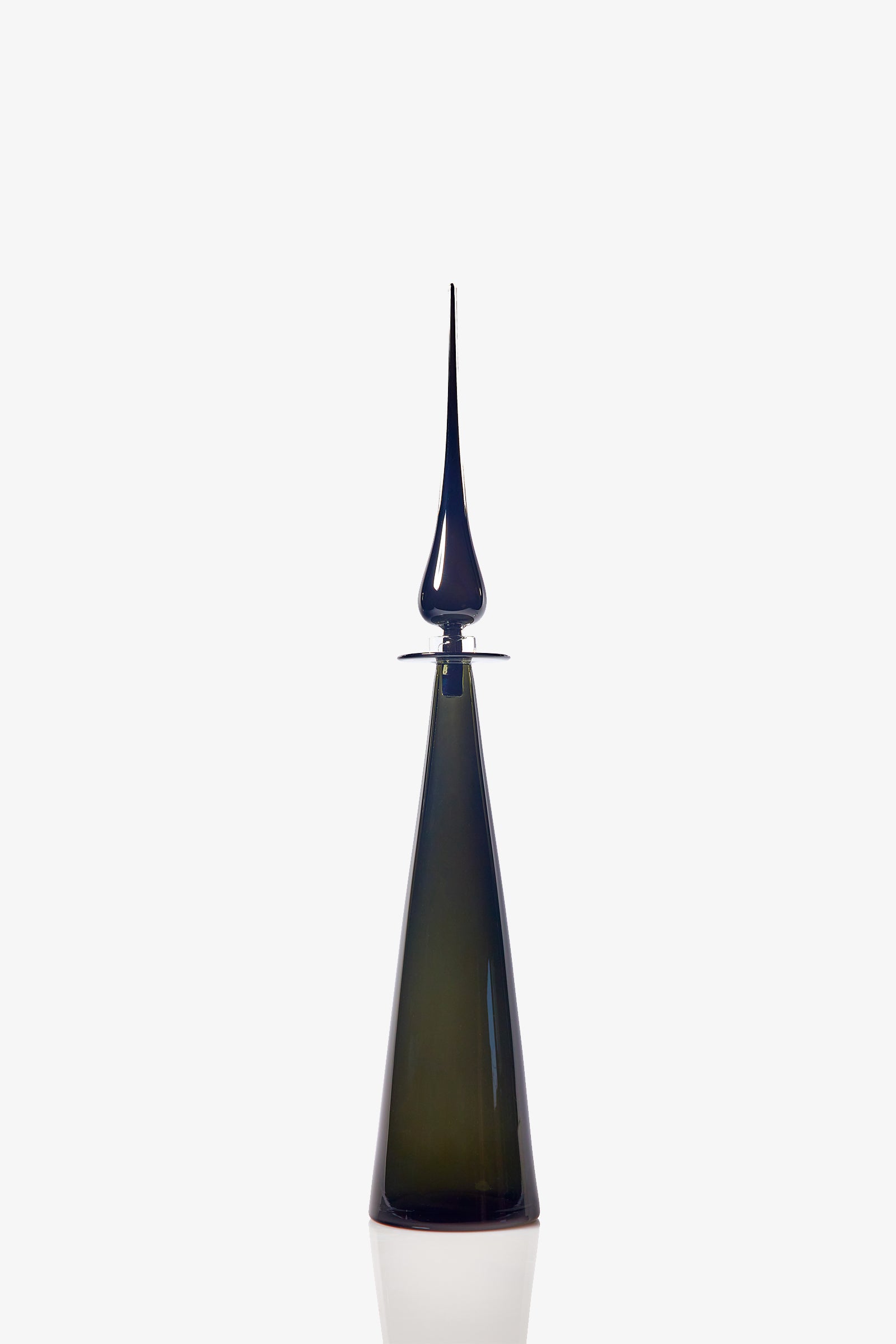 A sleek, modern Petite Straight Cone Decanter in tall, dark green glass with a pointed, elongated stopper stands against a plain white background. The decanter features a reflective surface and minimalist design.