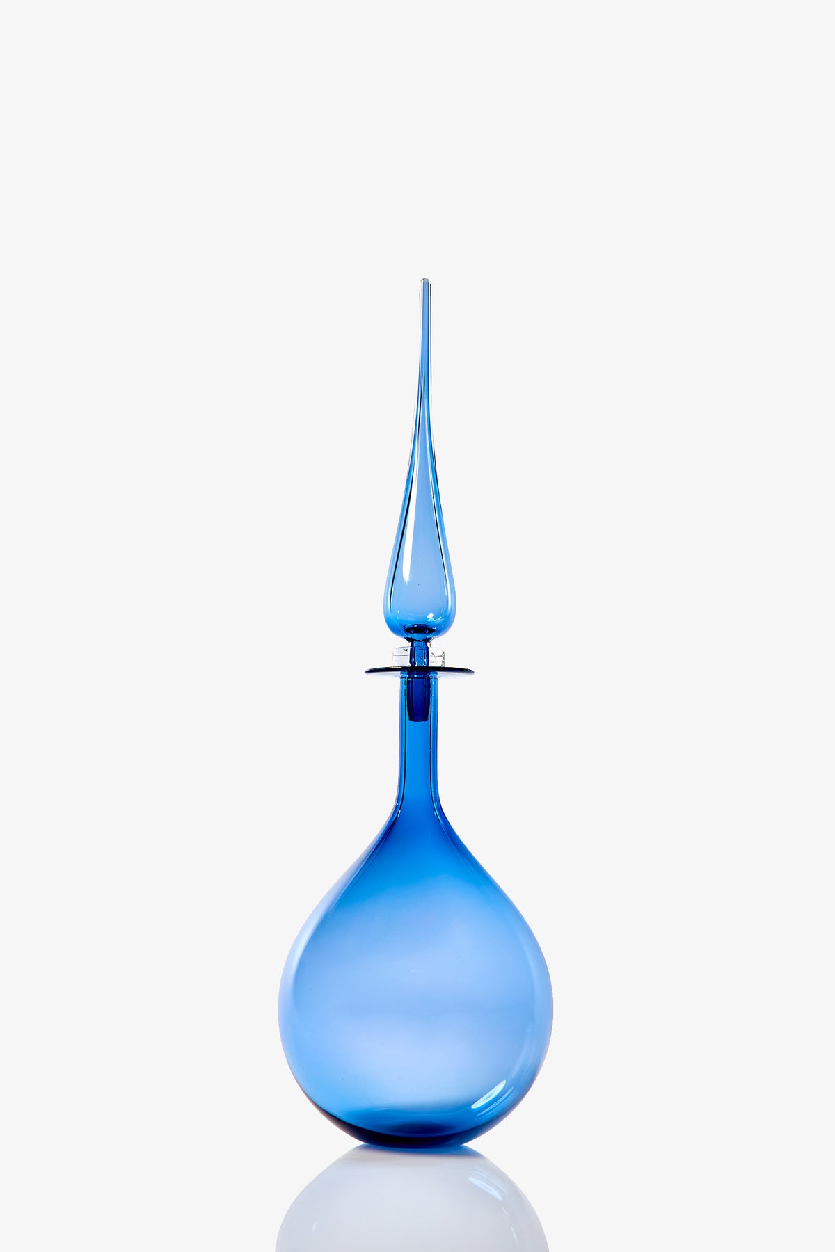 The Petite Tear Drop Decanter is a tall, elegant blue glass piece featuring a round base and an elongated stopper, displayed against a plain white background.