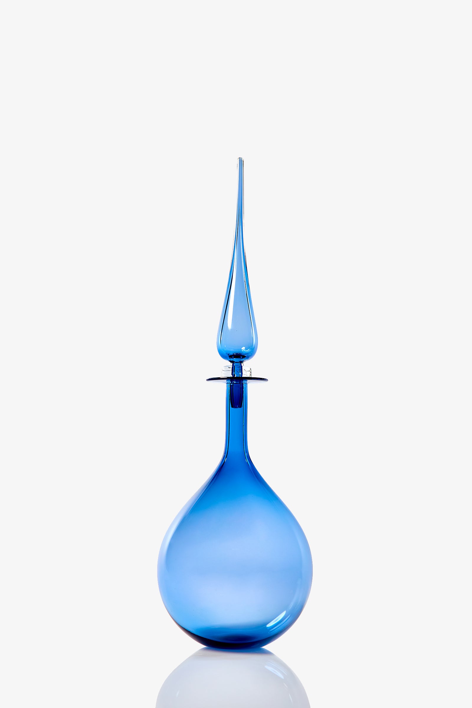 The Petite Tear Drop Decanter is a tall, elegant blue glass piece featuring a round base and an elongated stopper, displayed against a plain white background.
